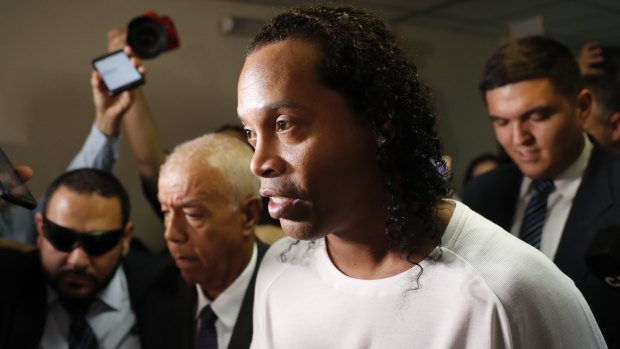 Former soccer star Ronaldinho is escorted by police. 