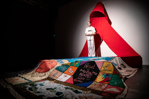 The set consists of an oversized red ribbon until the end of the play when a portion of the AIDS quilt is rolled out.