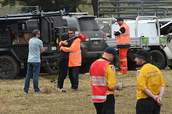 Lily’s father Jim, wearing an orange high vis jacket, is embraced at the command post on Thursday.