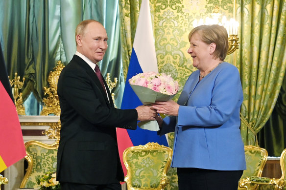 Russian President Vladimir Putin, left, presents flowers to German Chancellor Angela Merkel during their meeting in the Kremlin in Moscow, Russia.