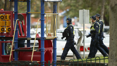 A police patrol walks past a playground in Melbourne.