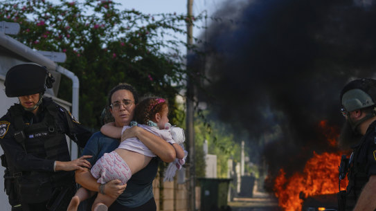 Police officers evacuate a woman and a child from a site hit by a rocket fired from the Gaza.
