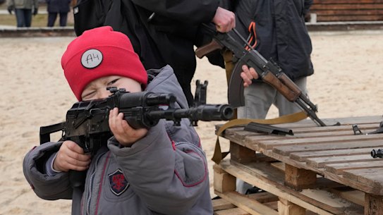 A boy plays with a weapon while an instructor shows a Kalashnikov assault rifle during a training of members of a Ukrainian far-right group train, in Kyiv, Ukraine.