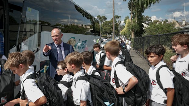 Brett Collison, the director of junior school at Xavier College, with students who travel home on school buses.
