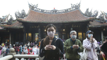 People wear face masks to protect against the spread of the coronavirus as they pray in Taipei, Taiwan.