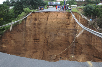 Stranded people stand in front of a bridge that was swept away in Ntuzuma, outside Durban, South Africa, on Tuesday.