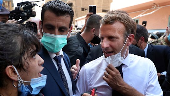 French President Emmanuel Macron, right, speaks with a woman as he visits the Gemayzeh neighbourhood, which suffered extensive damage.
