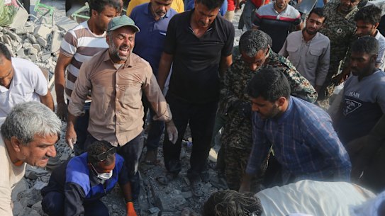 Soccorritori e residenti cercano tra le macerie all'indomani di quello che i funzionari iraniani hanno definito un attacco israelo-americano contro una scuola elementare femminile a Minab, in Iran, sabato. 