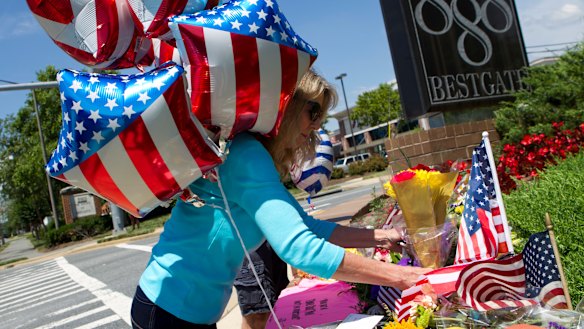 Kathaleen Novick place flowers at makeshift memorial in the scene were five journalists were shot dead.