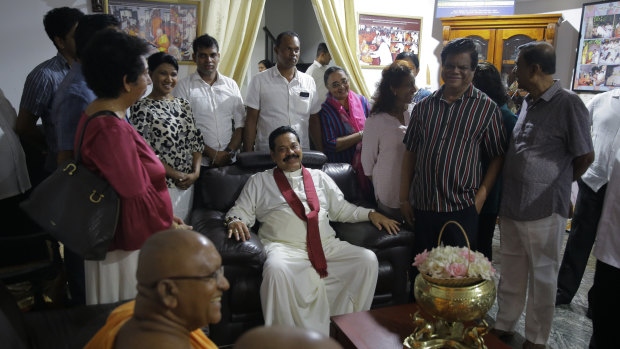 Mahinda Rajapaksa (centre) talks with supporters at a Buddhist temple in Colombo.