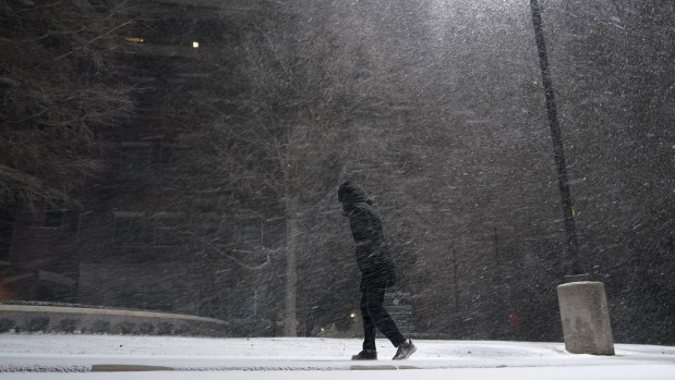 A woman walks through falling snow in San Antonio.