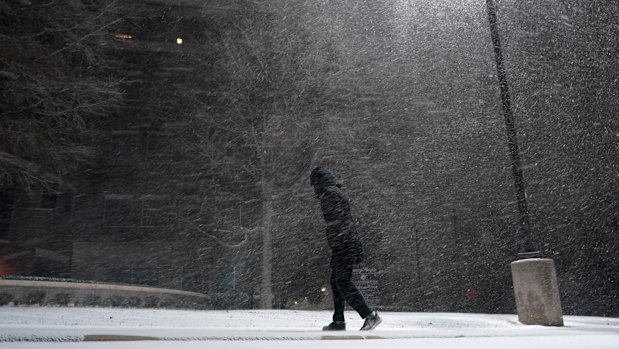 A woman walks through falling snow in San Antonio.