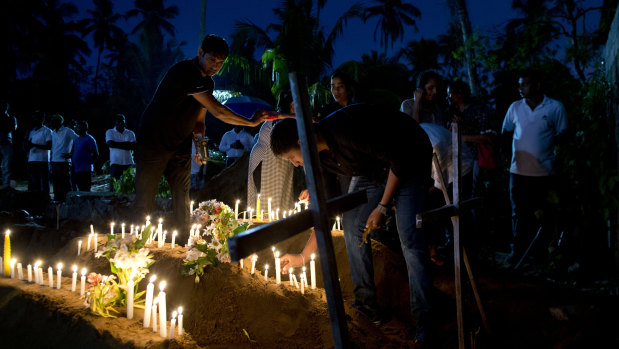 Relatives light candles after the burial of three victims of the same family, who died at Easter Sunday bomb blast at St. Sebastian Church in Negombo, Sri Lanka.