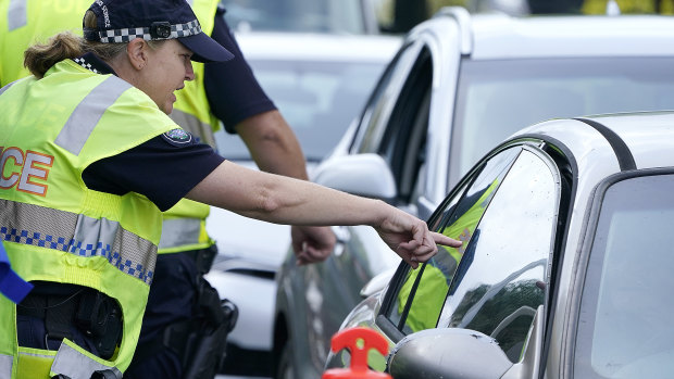A police officer gestures to a driver at a checkpoint at Coolangatta on the Queensland-NSW border.