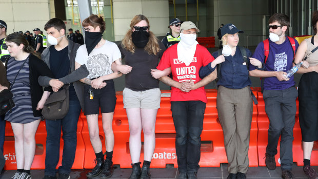 Protesters in face masks lock arms to try and stop people entering the convention centre. 