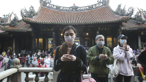 People wear face masks to protect against the spread of the coronavirus as they pray in Taipei, Taiwan.