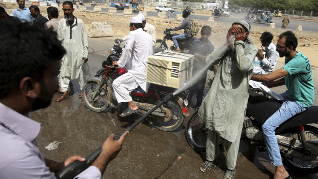 People volunteer to be sprayed in Karachi, Pakistan, as the mercury climbed well into the 40s this month.