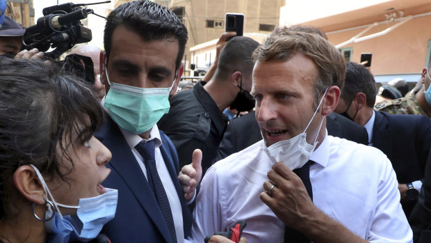 French President Emmanuel Macron, right, speaks with a woman as he visits the Gemayzeh neighbourhood, which suffered extensive damage.