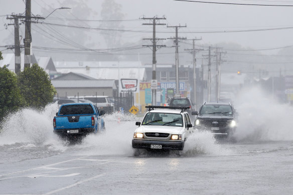 Cars drive through a flooded road in Whangarei, in northern New Zealand, on Sunday.