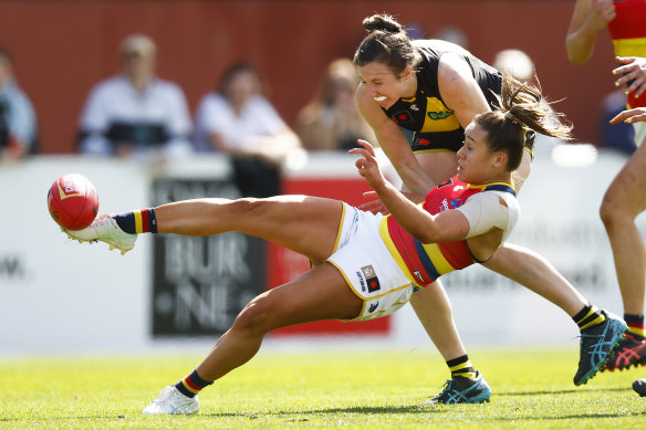 Hannah Munyard of the Crows kicks while being tackled by Rebecca Miller.