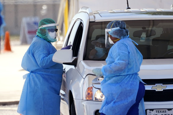 Healthcare workers administer COVID-19 tests at a drive-through site in San Antonio, Texas.