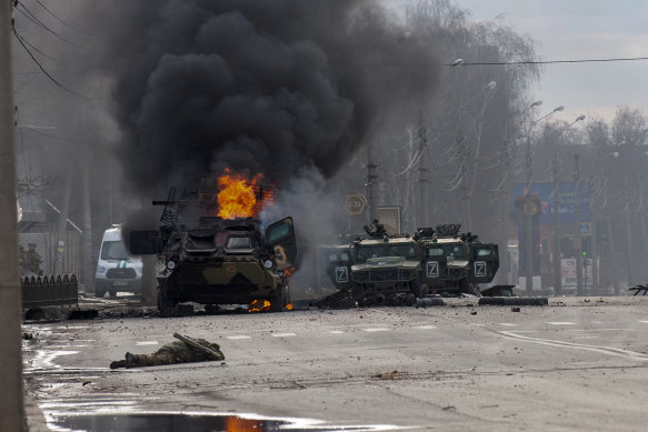 A Russian armoured personnel carrier burns in Kharkiv - with what appears to be a body in the foreground.