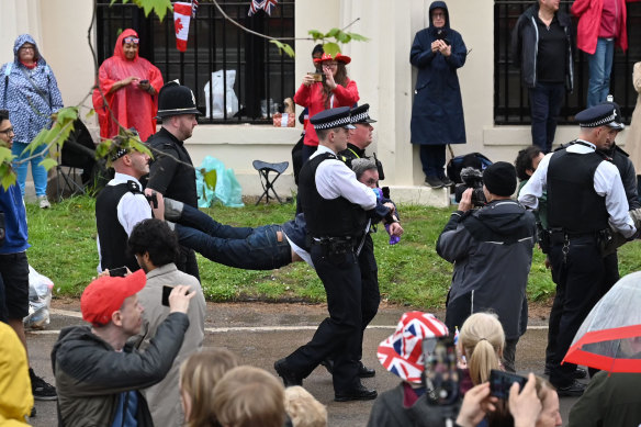 Police arrest protesters near the King’s procession on Saturday.