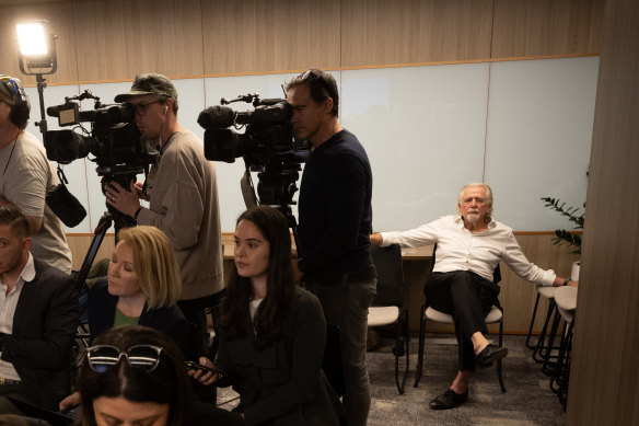 Woodman takes a seat at the back of the room at the end of the press conference.