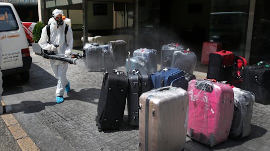 A worker sprays disinfectant on luggage outside a hotel in Beirut. 