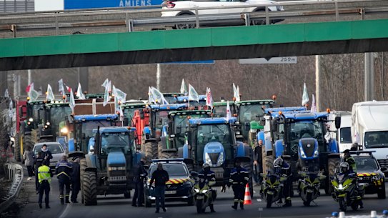 Police forces monitor a farmers demonstration on a highway leading to Paris.