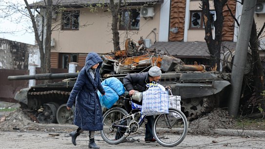Residents walk past a destroyed tank in an area of Mariupol controlled by Russian-backed separatist forces.