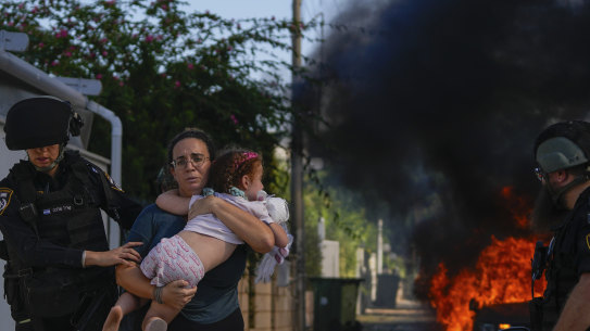 Police officers evacuate a woman and a child from a site hit by a rocket fired from the Gaza Strip, in Ashkelon.
