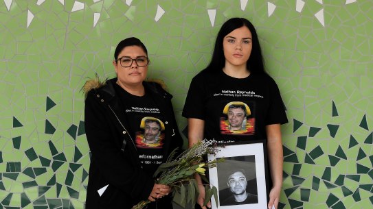 Taleah (left) and Makayla Reynolds hold a portrait of their brother, Nathan.