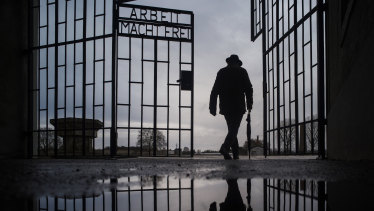 A man walks through the gate of the Sachsenhausen Nazi death camp with the phrase 'Arbeit macht frei' (work sets you free) in Oranienburg, Germany, on International Holocaust Remembrance Day.