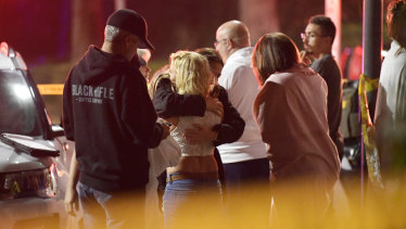 People comfort each other as they stand near the scene in Thousand Oaks, California, where a gunman opened fire inside a country dance bar crowded with hundreds of people on "college night". 
