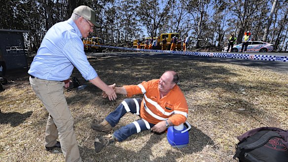 Australian Prime Minister Scott Morrison shakes hands with an emergency services worker taking a rest during a visit to the bushfire affected area of Binna Burra.