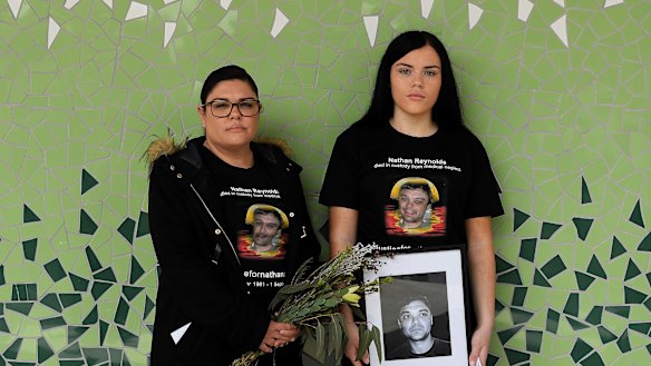 Taleah (left) and Makayla Reynolds hold a portrait of their brother, Nathan.