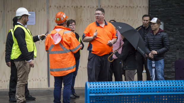 Residents speak to officials outside the Bourke Street apartment building on Monday.