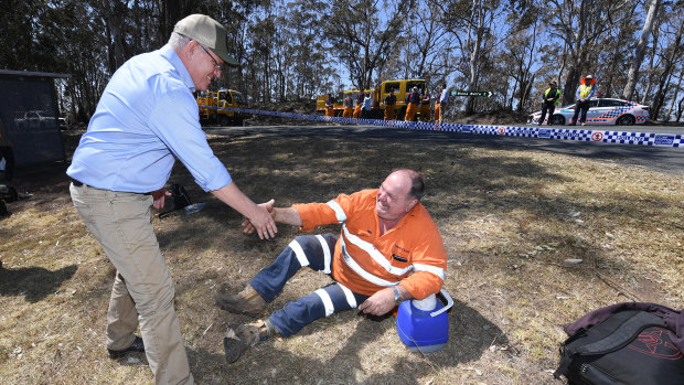 Australian Prime Minister Scott Morrison shakes hands with an emergency services worker taking a rest during a visit to the bushfire affected area of Binna Burra.