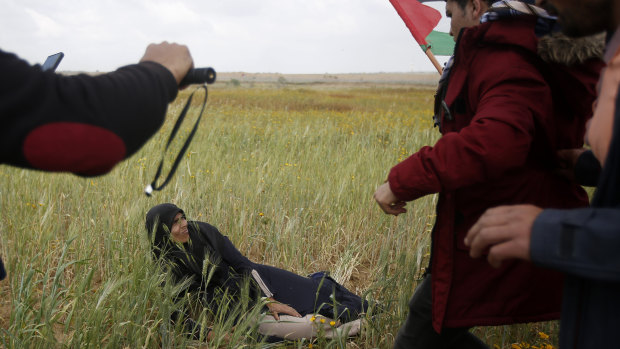 Palestinian protesters try to evacuate a wounded woman during clashes with Israeli troops along the Gaza Strip border.