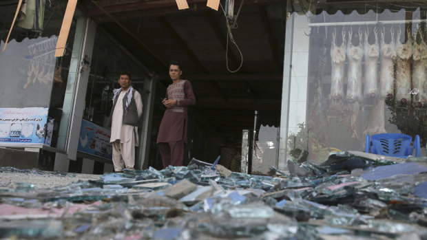 Afghans stand near a damaged shop after the explosion. 