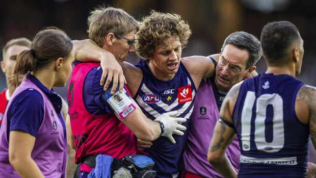 Out of action: Fremantle caption Nat Fyfe is escorted off the ground after a clash of heads, and didn't return to the game.