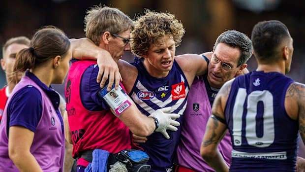 Out of action: Fremantle caption Nat Fyfe is escorted off the ground after a clash of heads, and didn't return to the game.