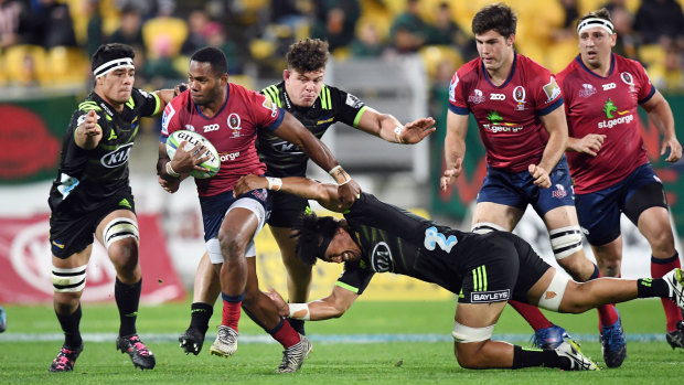 Filipo Daugunu of the Reds (left) evades a tackle of Ardie Savea of the Hurricanes during the round 14 Super Rugby clash on Friday.