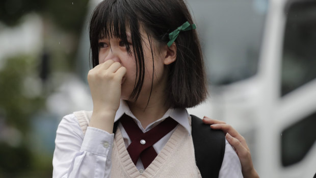 A woman sheds tears as she visits a makeshift memorial honouring the victims of Thursday's fire at the Kyoto Animation Studio.