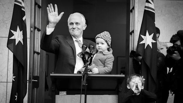 Malcolm Turnbull, holding granddaughter Alice, waves goodbye as grandson Jack plays with the media. 
