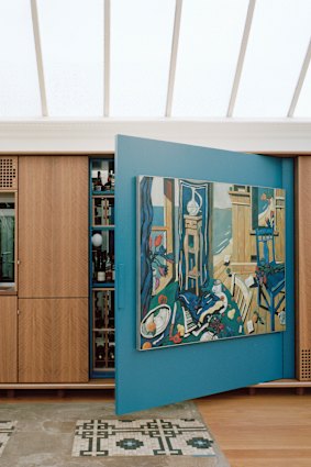 A large sliding panel, complete with an abstract painting, moves to conceal the kitchen.
