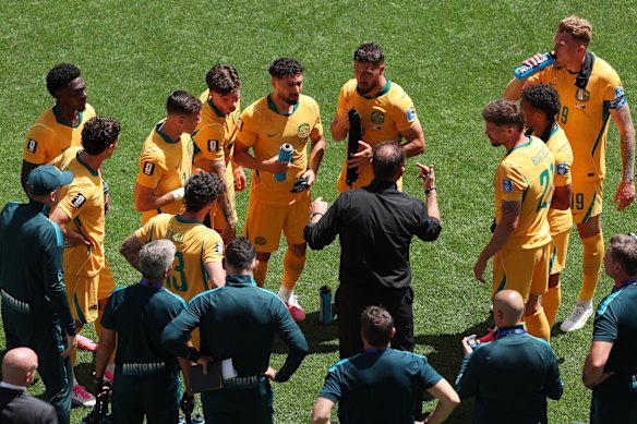 Australia head coach Tony Popovic, centre, speaks to his players during the hydration break.