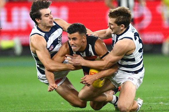 Oisin Mullin and Tom Atkins both try and bring Nick Daicos to ground.