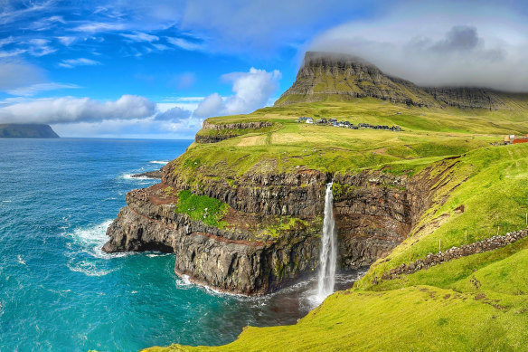 Incredible greenery ices the cliffs surrounding Mulafossur Waterfall.